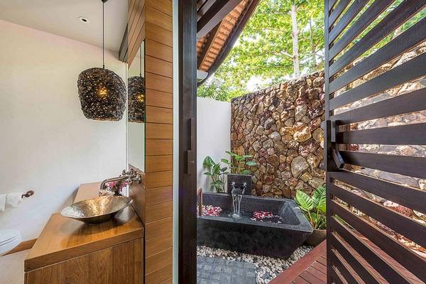 Ein Badezimmer im Tubkaak Krabi Boutique Resort mit einer freien Badewanne, einer Steinmauer und einer Holzdecke.