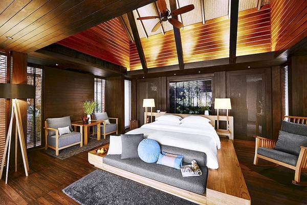 Schlafzimmer im Tubkaak Krabi Boutique Resort mit Holzwänden, Bett, Sesseln und Deckenventilator.