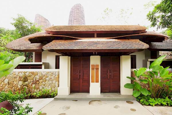 Vorderansicht des Tubkaak Krabi Boutique Resorts mit zwei hölzernen Eingangstüren und einem Dach aus Stroh.