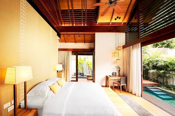 Innenansicht eines Schlafzimmers im Tubkaak Krabi Boutique Resort mit Bett, Tisch und Swimmingpool.
