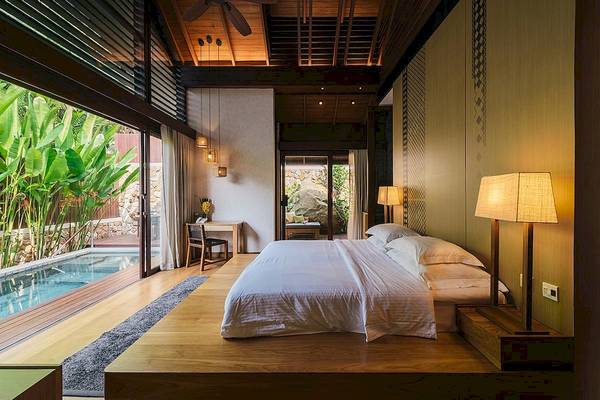 Das Schlafzimmer mit einem Bett, einem Tisch und einem Pool im Tubkaak Krabi Boutique Resort.