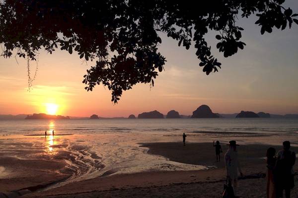 Abendstrandszene mit Personen und Sonnenuntergang am Tubkaak Krabi Boutique Resort