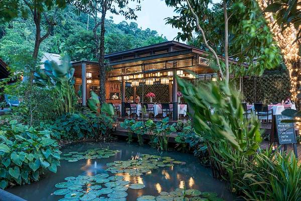 Außenbereich des Tubkaak Krabi Boutique Resorts mit Restaurant, Tischen, Stühlen und Wasserpflanzen.