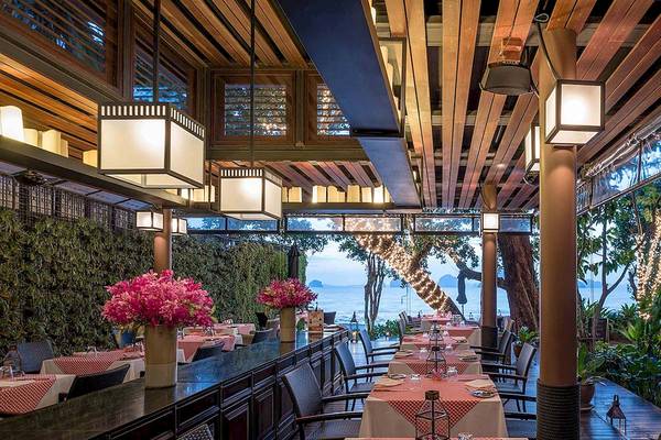 Innenansicht des Restaurants im Tubkaak Krabi Boutique Resort mit Tischen, Stühlen und Blumenvasen.