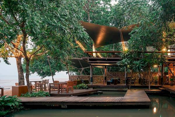 Außenbereich des Tubkaak Krabi Boutique Resorts mit hölzerner Terrasse und beleuchteten Bäumen.