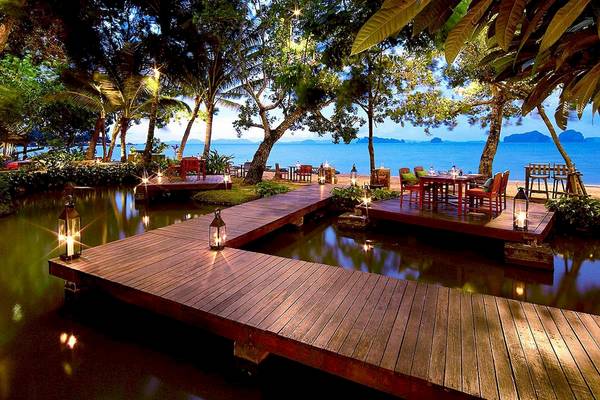 Außenbereich des Tubkaak Krabi Boutique Resorts mit Esstischen am Wasser und Laternen