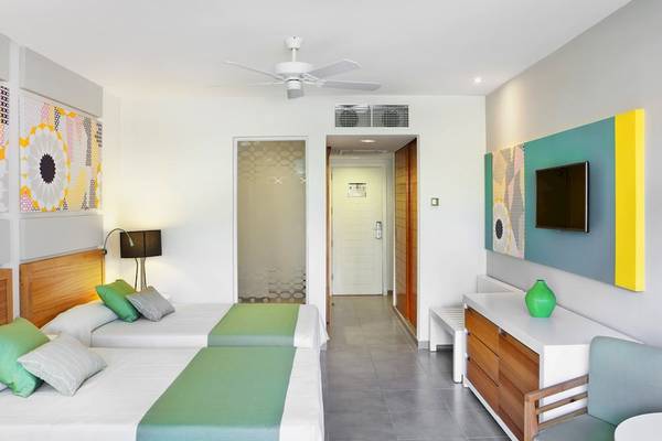 Zwei Betten mit grünen Kissen in einem modernen Zimmer im Playa Vista Azul Varadero Hotel.