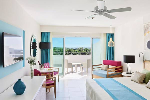 Hotelzimmer des Playa Vista Azul Varadero mit Balkon, Bett, Möbeln und Panoramafenstern.
