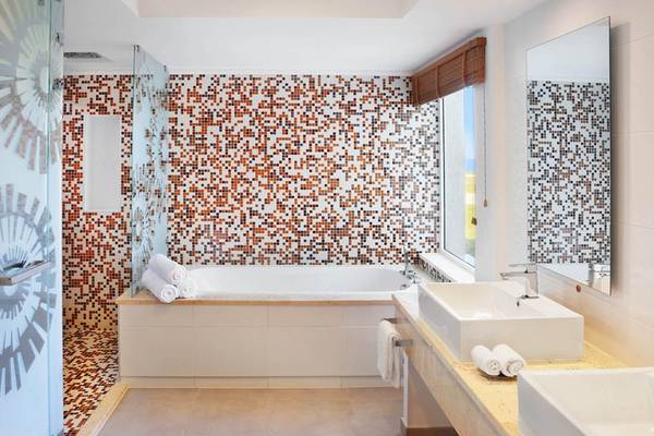 Ein Badezimmer mit einer Badewanne und einer braun-weiß gemusterten Fliesenwand.