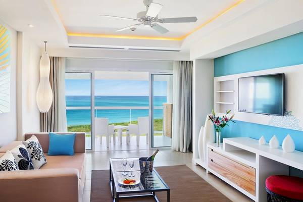 Wohnzimmer mit Meerblick im Playa Vista Azul Varadero Hotel, mit Sofa, Tisch, Fernseher und Balkon.