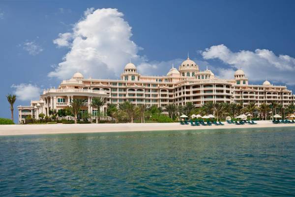 Außenansicht des Kempinski Hotel Residences Palm Jumeirah mit weißen Gebäuden und Palmen am Strand.