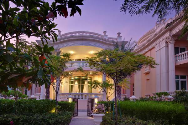 Außenansicht des Kempinski Hotel Residences Palm Jumeirah mit gut beleuchtetem Eingang und Garten.