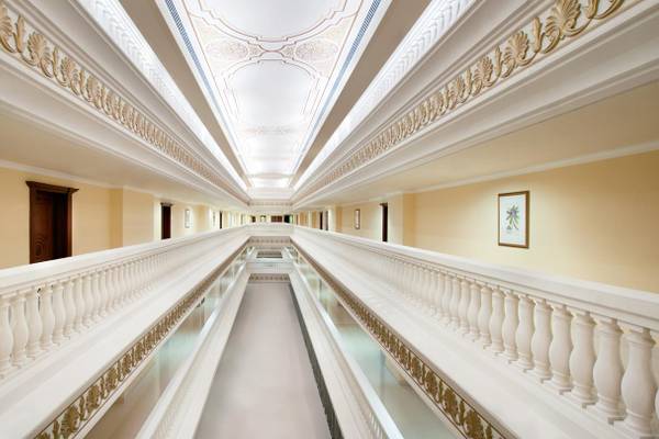Innenansicht des Flurs im Kempinski Hotel Residences Palm Jumeirah mit weißen Säulen und goldenen Verzierungen.