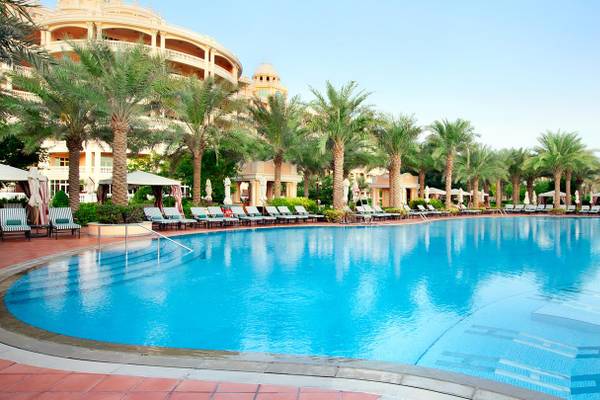 Außenpool des Kempinski Hotel Residences Palm Jumeirah mit Sonnenliegen und Palmen.
