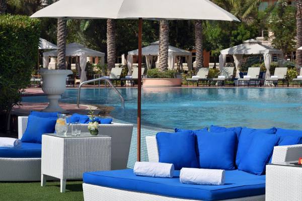 Poolbereich im Kempinski Hotel Residenzen Palm Jumeirah mit blauen Liegen und weißen Sonnenschirmen.