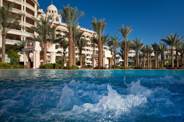 Schwimmbad des Kempinski Hotel Residences Palm Jumeirah mit Palmen und Gebäuden im Hintergrund.
