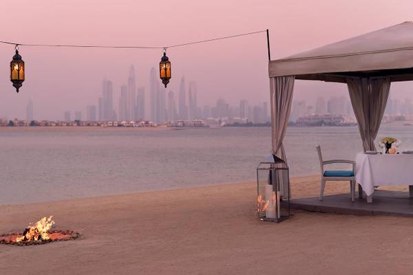 Romantisches Dinner am Strand im Kempinski Hotel Residences Palm Jumeirah mit einem Tisch, einem Pavillon und einem Feuer.