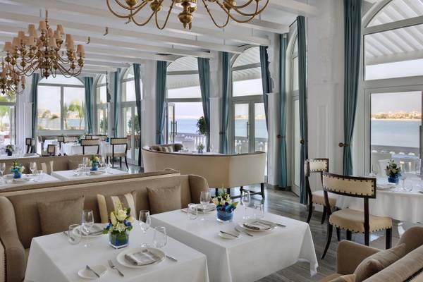 Innenansicht des Restaurants im Kempinski Hotel Residences Palm Jumeirah mit eleganten Tischen, Stühlen und Blick auf das Meer.