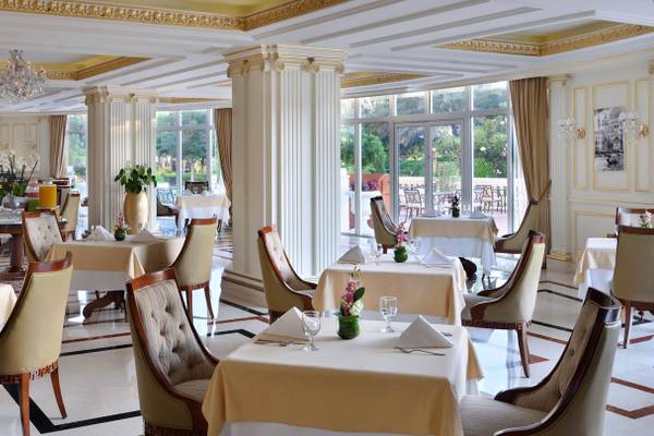 Innenansicht des Restaurants im Kempinski Hotel Residenzen Palm Jumeirah mit eleganten Tischen, Stühlen und Blumenarrangements.