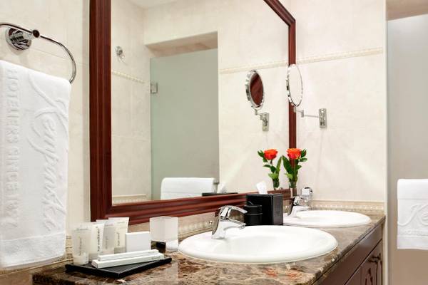 Ein Badezimmer mit zwei Waschbecken im Kempinski Hotel Residences Palm Jumeirah, mit einem großen Spiegel, Blumen und Handtüchern.