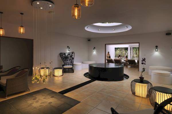 Innenbereich des Cocoon Maldives Hotels mit Loungebereich, Couch und Lichtinstallationen.
