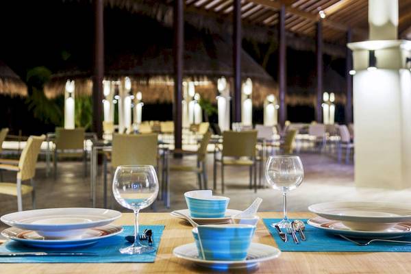 Ein Tisch im Cocoon Maldives Hotel Restaurant mit Tellern, Tassen und Gläsern.