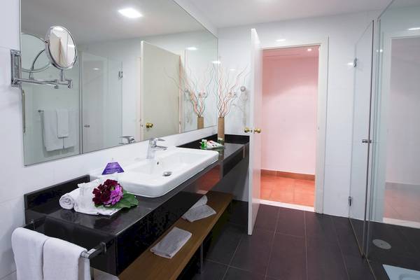 Badezimmer im Fuerteventura Princess Hotel mit Spiegel, Waschbecken und offenen Türen zur Dusche.