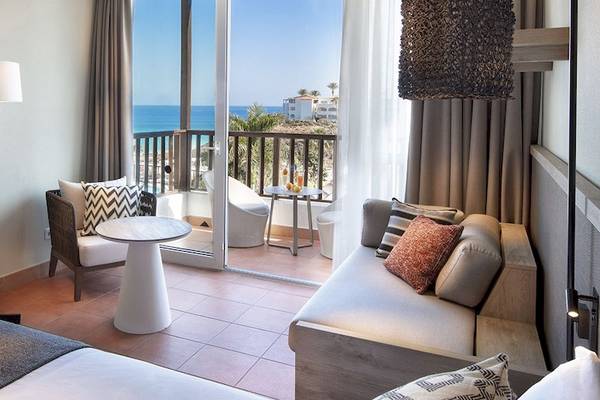 Innenansicht einer Suite im Fuerteventura Princess Hotel mit Blick auf den Ozean und einem möblierten Balkon.