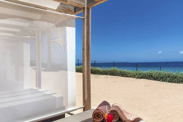 Außenbereich des Fuerteventura Princess Hotels mit einem Strandbett, Strandtüchern und einem kühlen Getränk.