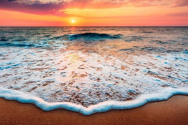 Sonnenuntergang am Strand, sanfte Wellen treffen auf den Sand, Fuerteventura Princess Hotel im Hintergrund.