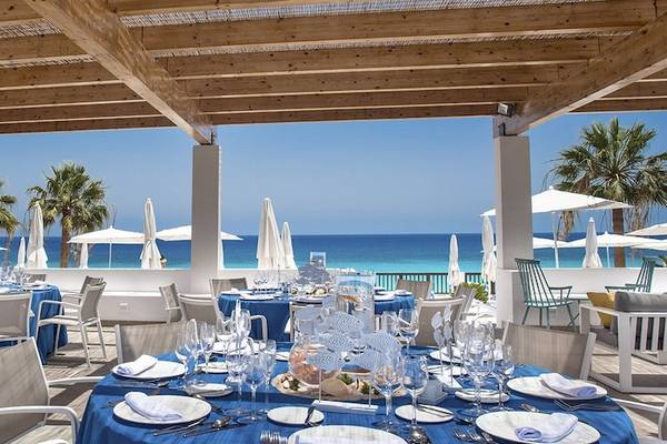 Außenbereich des Fuerteventura Princess Hotels mit blauen Tischen und Stühlen, Blick auf das Meer.