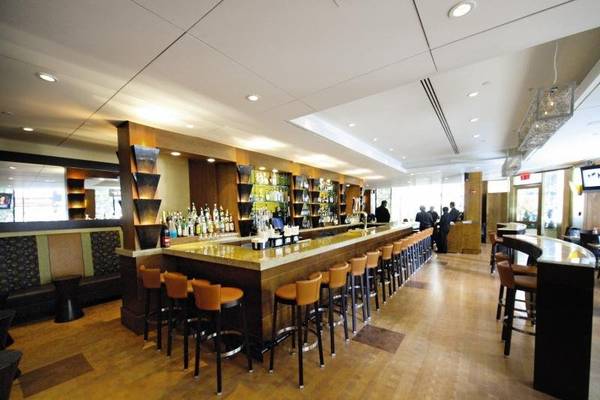 Die Bar im New Yorker Hotel mit gepolsterten Stühlen und einer Theke voller Flaschen.