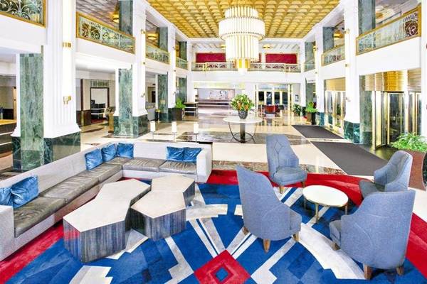 Lobbybereich des New Yorker Hotels mit blauen Stühlen, einer großen Couch und einem großen Teppich.