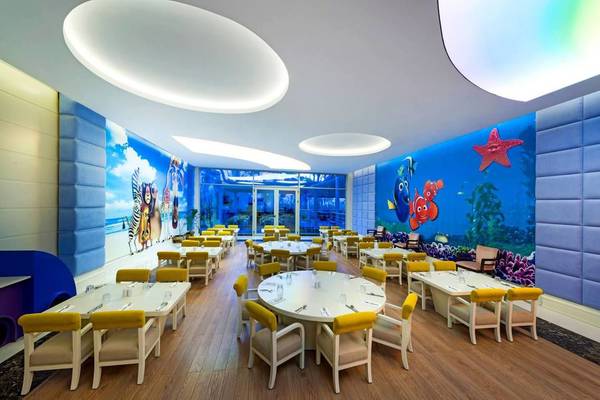Innenbereich eines Restaurants im Vogue Hotel Supreme Bodrum mit bunten Wänden und runden Tischen.