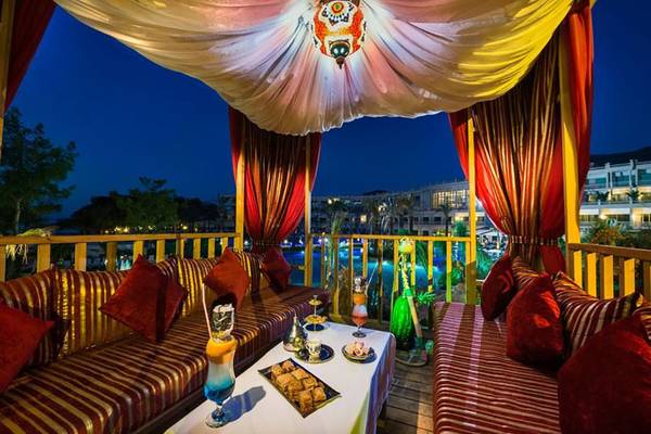 Loungebereich des Vogue Hotel Supreme Bodrum mit roten Vorhängen und orientalischen Möbeln bei Nacht.