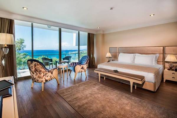 Suite im Vogue Hotel Supreme Bodrum mit Meerblick, inklusive Schlafzimmer, Wohnzimmer, Balkon und modernen Möbeln.