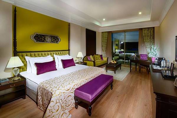 Schlafzimmer im Vogue Hotel Supreme Bodrum mit einem großen Bett, gelben Wänden und Möbeln.