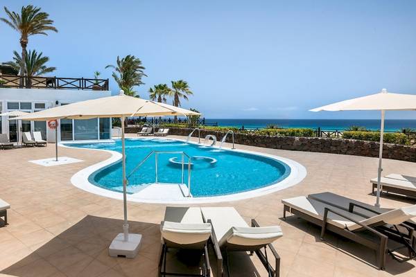 Poolbereich im Occidental Jandia Royal Level Hotel mit Sonnenliegen, Sonnenschirmen und Meerblick.