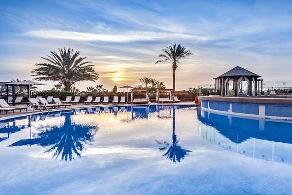 Sonnenuntergang am Pool des Occidental Jandia Royal Level mit Lounge-Sesseln und Palmen.