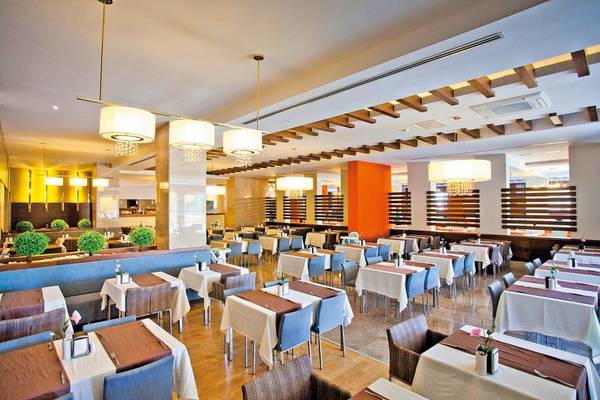 Restaurant des Seher Sun Palace Resort & Spa mit gedeckten Tischen, modernen Kronleuchtern und blauen Stühlen.