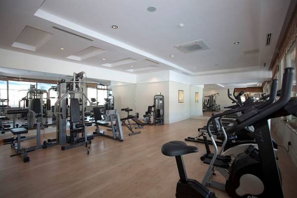 Fitnessstudio im Seher Sun Palace Resort & Spa mit vielen Geräten und Holzboden.