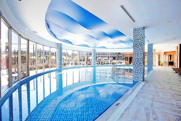 Ein großer Swimmingpool im Seher Sun Palace Resort & Spa mit blauen Fliesen und einer Glasfassade.