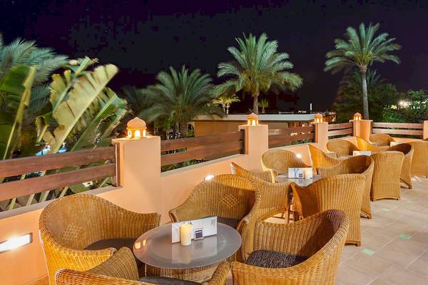 Abendterrasse des Occidental Jandia Royal Level Hotels mit Palmen, Tischen und Stühlen.