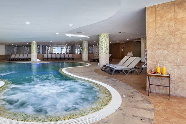 Innenpool im Occidental Jandia Mar Hotel mit Lounge-Liegestühlen und Wasserspender.