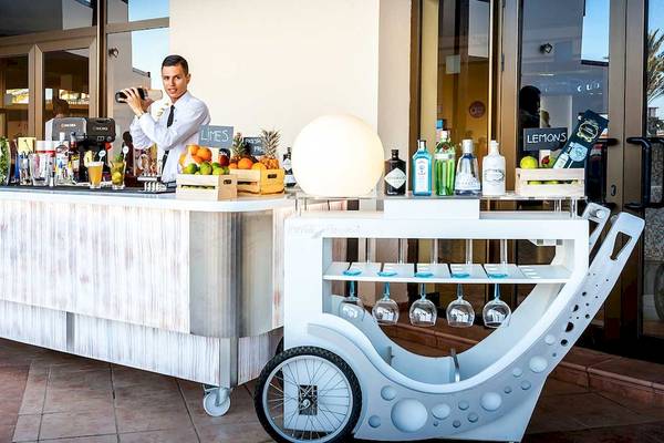 Ein Barwagen vor dem Occidental Jandia Mar Hotel mit verschiedenen Getränken und Früchten.