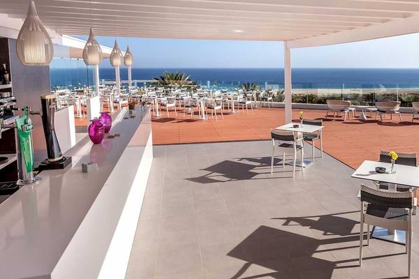 Hotelterrasse mit Blick auf das Meer und viele Tische und Stühle draußen.
