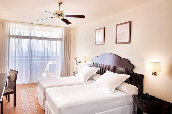 Zwei-Betten-Zimmer im Occidental Jandia Mar Hotel mit weißen Möbeln, Deckenventilator und Fernseher.