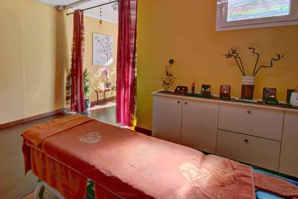 Massageraum im SBH Monica Beach Resort mit gelben Wänden, rotem Vorhang und Massagetisch.