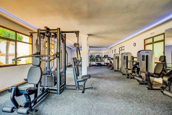 Fitnesscenter im SBH Monica Beach Resort mit verschiedenen Geräten und Fenstern.