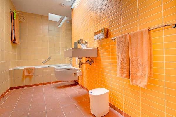 Badezimmer im SBH Monica Beach Resort mit gelben Fliesen, Badewanne und Toilette.